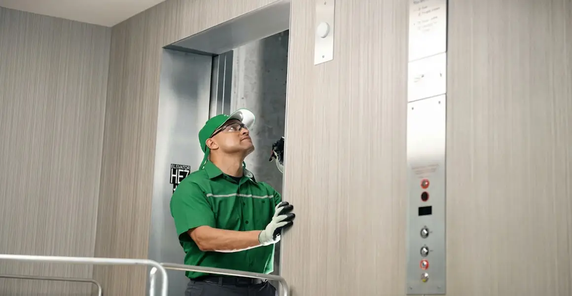 Professional technician in safety gear inspecting elevator shaft during installation or maintenance service in Riyadh.