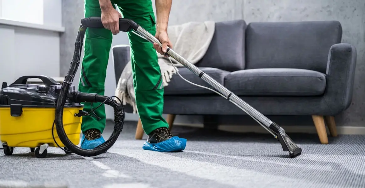 Professional carpet cleaning technician using extractor machine on living room carpet in Riyadh.