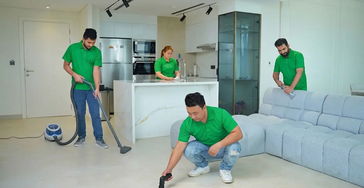 Professional deep cleaning team in green uniforms vacuuming floors and wiping surfaces in a modern Riyadh apartment.